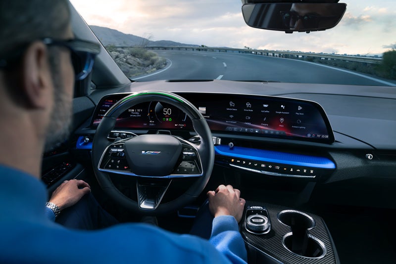 Front View of the 2026 OPTIQ-V Driving Through the Dusk Utilizing its Headlights | Suttle Cadillac in NEWPORT NEWS VA